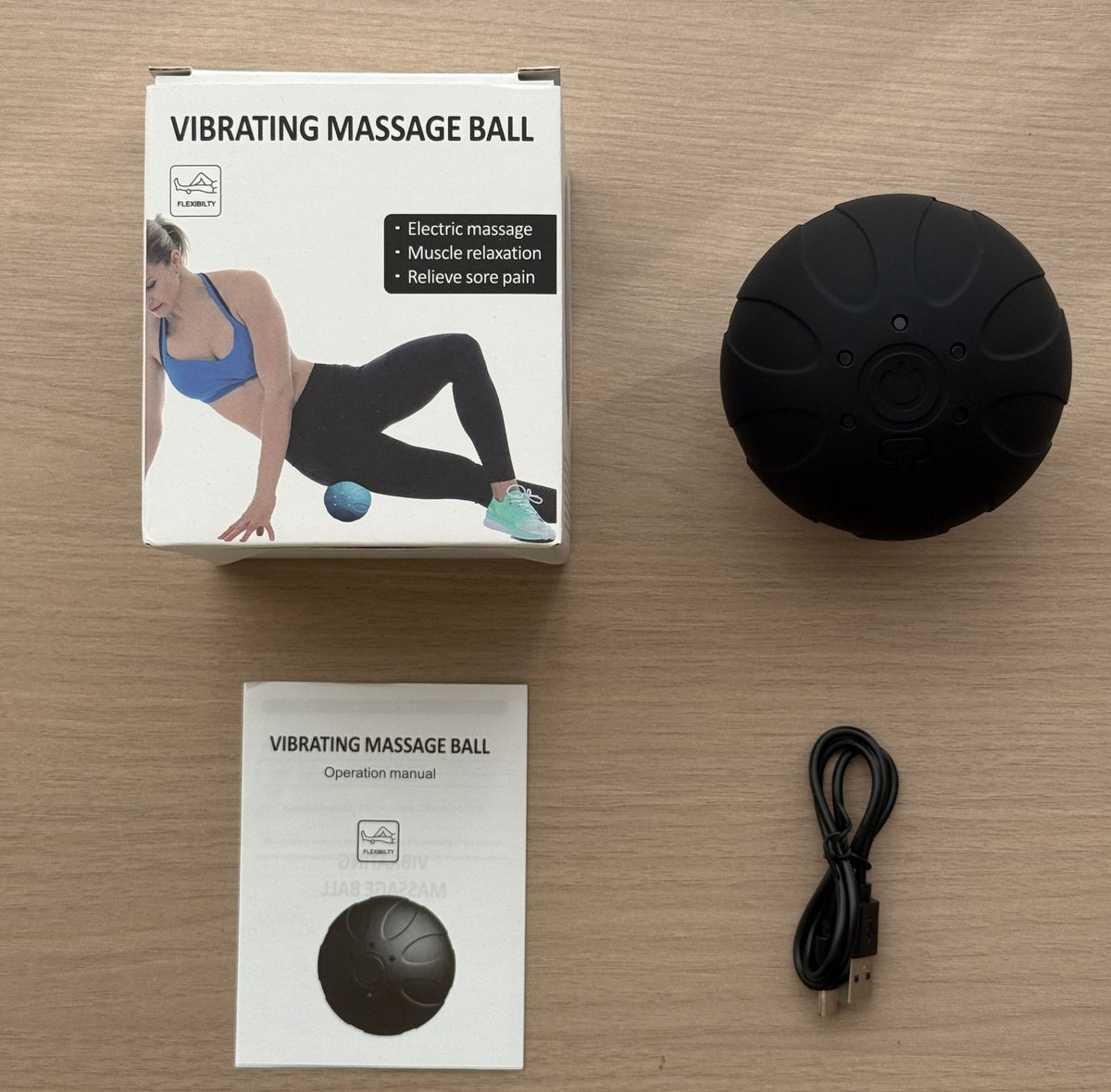 Bola de masaje negra con su caja y cable de carga